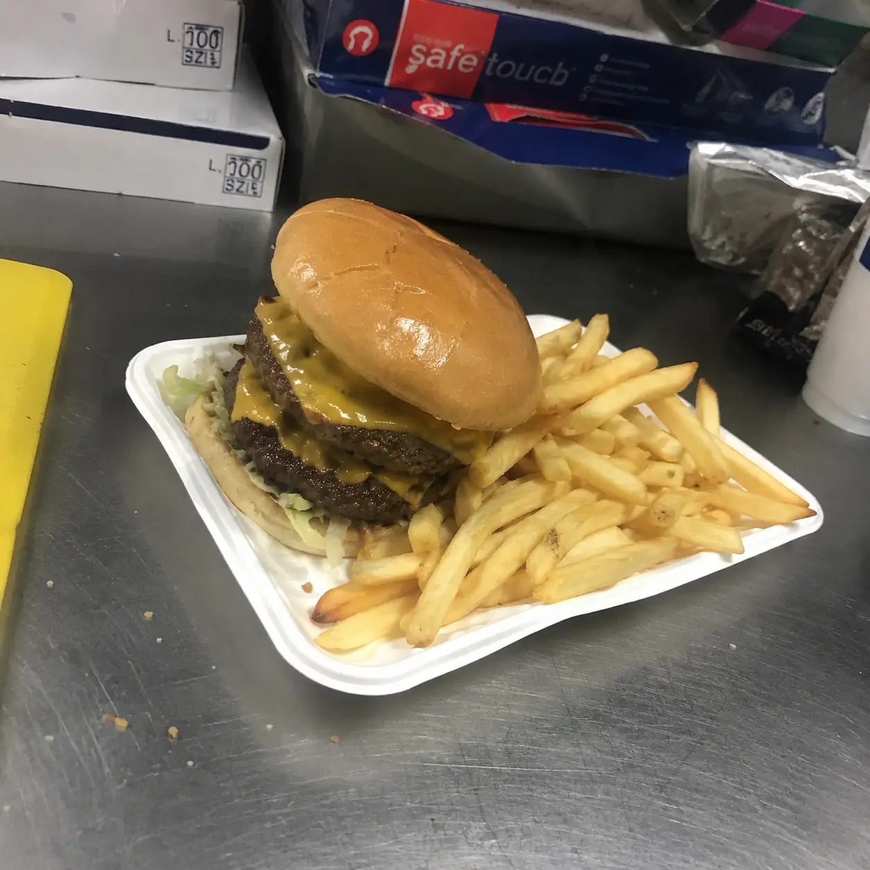 Amateur phone snapshot of a cheeseburger and fries on a takeaway counter